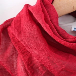 Macro shot of red cotton linen scarf showing natural crinkled texture and soft fabric detail