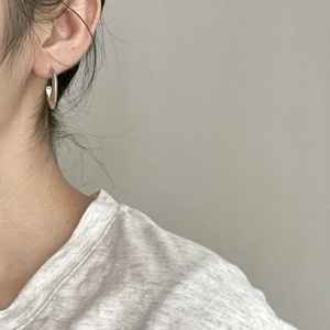 Close-up of minimalist silver U-shaped hoop earring worn on model's ear