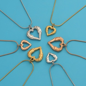 Three-tone stainless steel heart wing necklaces displayed on a blue background