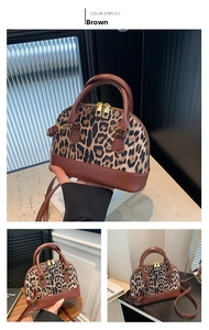 Detail view of leopard print shell bag with brown leather handles and golden dual zippers