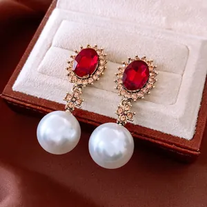 Vintage red gemstone and pearl drop earrings displayed on a dark velvet jewelry box