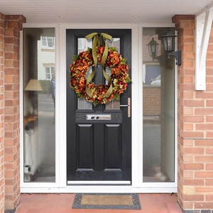 Couronne d'automne avec hortensias orange et rouges sur une porte d'entrée noire