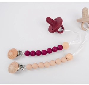 Detail of silicone and beech wood pacifier clips with octagonal beads in burgundy and beige