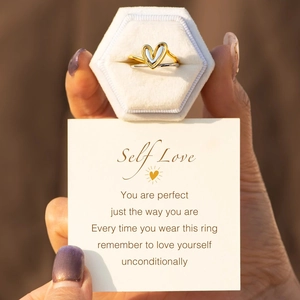 Detail of heart ring set on white velvet box held by hand with a greeting card