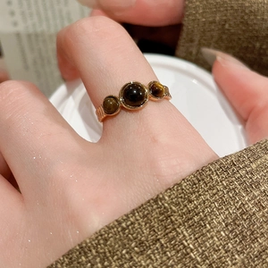 Macro shot of 18k gold plated ring with three round tiger eye stones on female finger