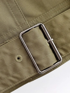 Detail of army green twill fabric and silver rectangular metal buckle on bomber jacket