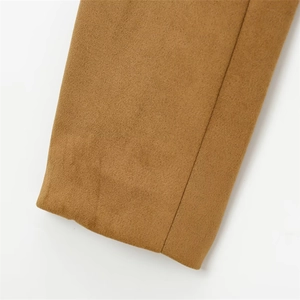 Gros plan sur la texture du tissu en laine camel et les coutures précises de la manche