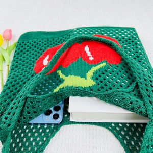 Green knit tote bag with red cherries showing interior storage for phone and books