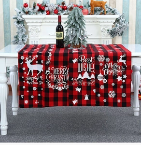Detail van een rood-zwarte geruite kersttafelloper met feestelijke prints en decor