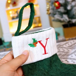 Detail of green knitted Christmas stocking with red letter Y embroidery and holly berries