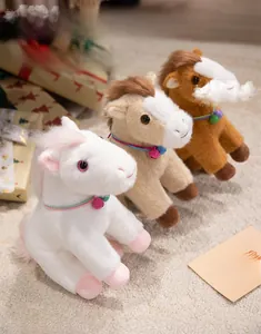 Detailed view of plush pony toys in white and brown with colorful collars and bells