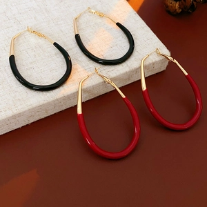 Close-up of red and black enamel oval hoop earrings with elegant gold metal clips