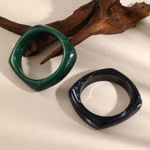 Detailed close-up of chunky resin bangles in green marble and black white patterns