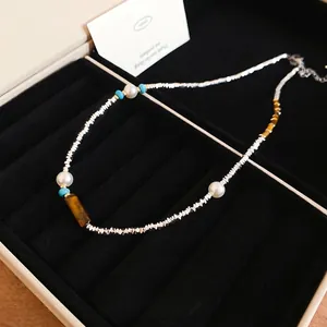 Ethnic style necklace with tiger eye stone, pearls and turquoise beads on black velvet