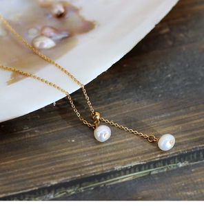Detailed close-up of natural white pearls and gold titanium chain on a wooden surface