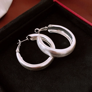 Close-up of silver brushed hoop earrings displayed in a black velvet jewelry box