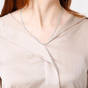 Primo piano di una collana bohémien con perline turchesi indossata da una modella in seta