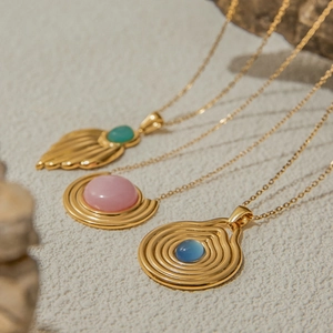 Detailansicht von drei goldenen Halsketten mit Türkis und rosa-blauen Edelsteinen