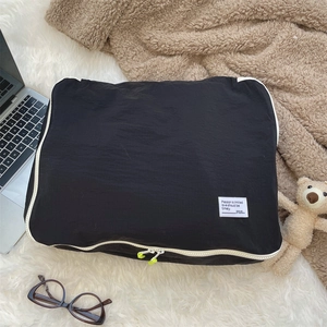 Close-up of black waterproof nylon storage bag with white zipper and green zipper pull