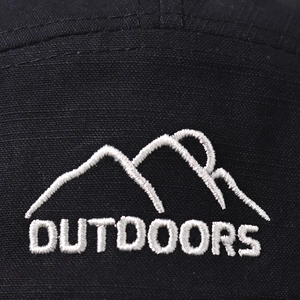 Detaillierte Makroansicht der weißen Bergstickerei auf einer schwarzen Outdoor-Kappe.