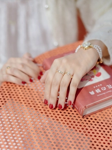 Japanese style white shell flower adjustable gold rings on hand with floral book background