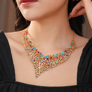 Detail of vintage gold necklace with colorful crystals in leaf design on a model