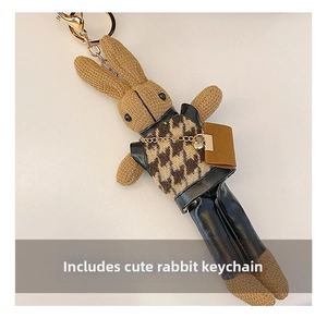 Close-up of a bunny plush bag charm with houndstooth vest and gold-tone chain accessory