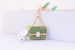 Detailed close-up of camellia handbag keychain with green rhinestones and white pearls
