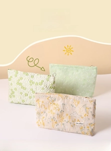 Macro detail of botanical embroidery on cotton linen makeup pouches with metal zipper