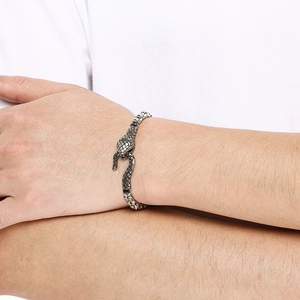 Detailed view of silver punk snake head chain bracelet worn on a male model's wrist