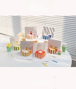 Dettaglio di biglietti d'auguri 3D colorati a forma di torta su un tavolo bianco