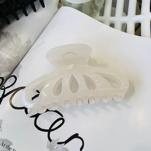 Hollow petal hair claw clip in creamy white resin displayed on a magazine
