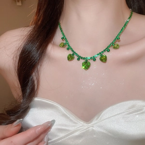 Close-up of green zircon heart pendant necklace with shimmering tassel details on model