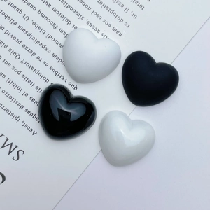 Detail showing heart-shaped resin charms in black and white with matte and glossy finishes