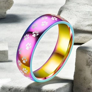 Makro-Detail eines Titanstahlrings mit Regenbogen-Farbverlauf und weißen Katzenpfoten-Motiven