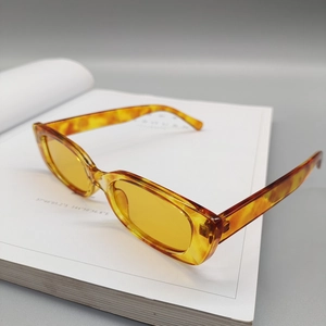 Detail of tortoise shell square sunglasses with yellow transparent lenses on book
