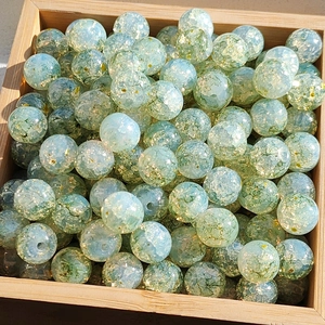 Macro shot of 8-10mm blue and green gold foil glaze glass beads in a wooden tray