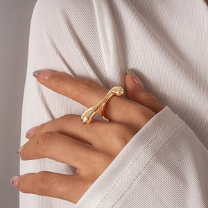 Macro detail of irregular gold liquid metal ring with a polished geometric streamline design