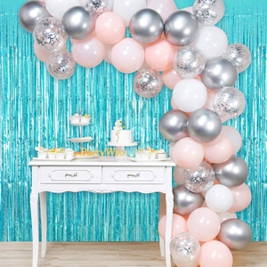 Detail of party balloon arch with sequins and light blue foil fringe curtain backdrop
