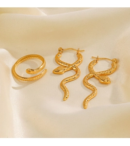 Detail of gold snake jewelry set with ring and earrings on beige silk background