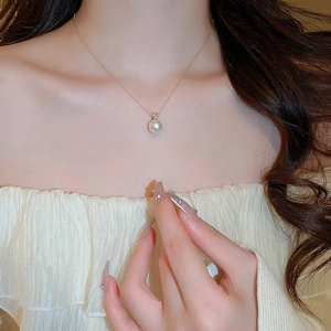 Detail of single round pearl necklace with zircon inlay on golden chain worn by model