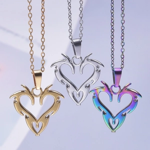 Three heart flame pendants in gold, silver, and rainbow steel on studio background
