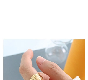 Macro shot of gold layered wavy textured ring on finger with polished metallic finish