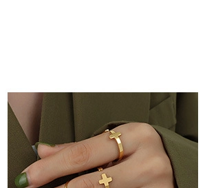 Close-up of 18K gold plated cross ring for women worn on finger with soft lighting