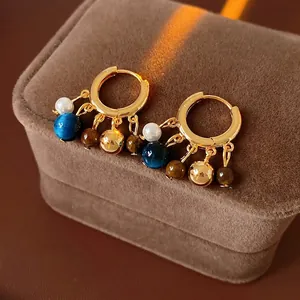 Vintage boho earrings with pearls, tiger eye beads and gold hoops on velvet