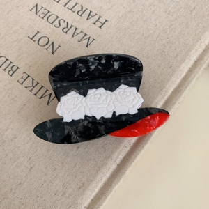 Macro detail of acetate cowboy hat hair claw clip with white roses and red accents