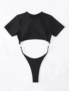 Flat lay of black cut-out one-piece swimsuit with silver metal rings on marble background