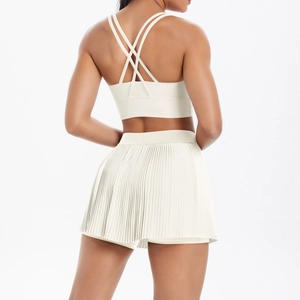 Detail view of cream white cross-back sports bra and pleated mini tennis skirt set