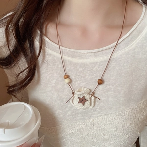 Detail of hand-woven star necklace with wooden beads on forest style clothing