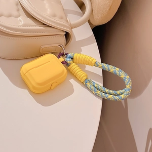 Yellow silicone AirPods Pro case with blue and yellow braided lanyard on a white surface